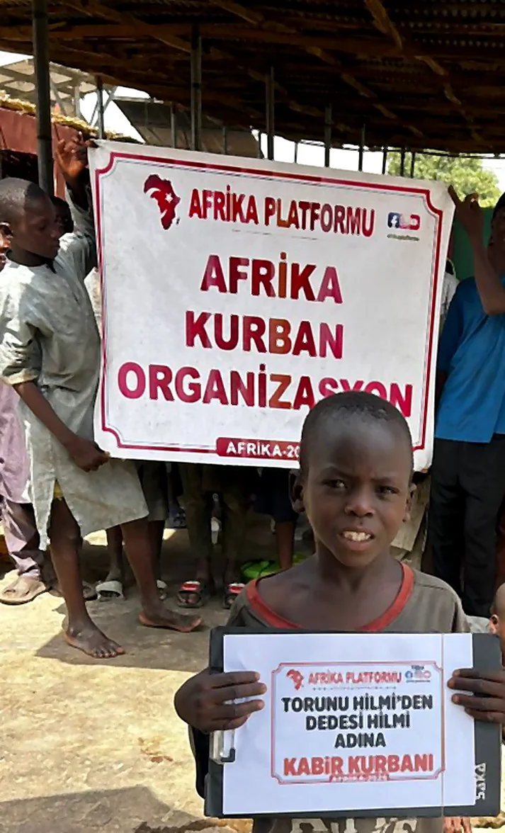Ein Kind hält im Namen seines Enkels und Großvaters in Afrika ein Grabopferzeichen